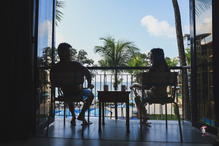 How to be an Elegant woman: Finally Seen, Heard, and Command Respect 25 A high-value couple relaxing on the balcony of their holiday resort in Seychelles enjoying each other's companies with blue sky, palm trees and beach in the backdrop, is an example of luxury travel.