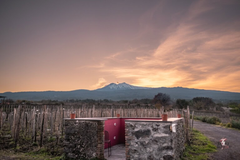 Exclusive trips to Mount Etna from catania: Elegant and Stress-free Options 2 Vineyard with Mount Etna in the background during sunset, scenic landscape in Sicily, with an outdoor BBQ area, taken during our trips to Mount Etna from Catania.